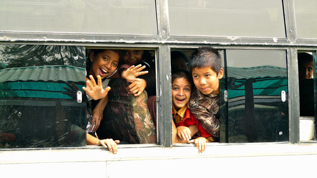 Kinderen in Nepal kijken blij omdat ze toeristen zien