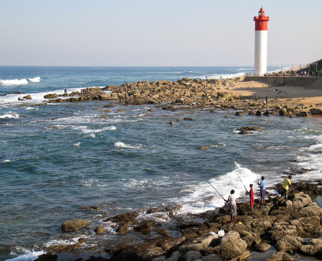 Vissers en vuurtoren aan de kust bij Durban.
