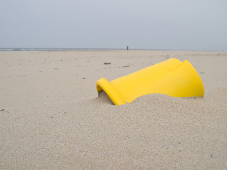 gele emmer in het zand