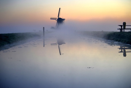De molen in de ochtend mist met opkomende zo'n