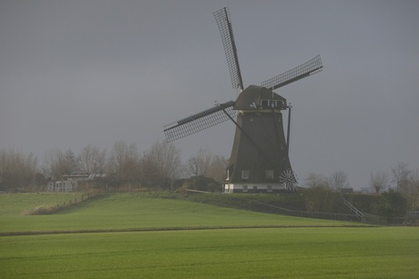 Molen in de mist met een mager zonnetje