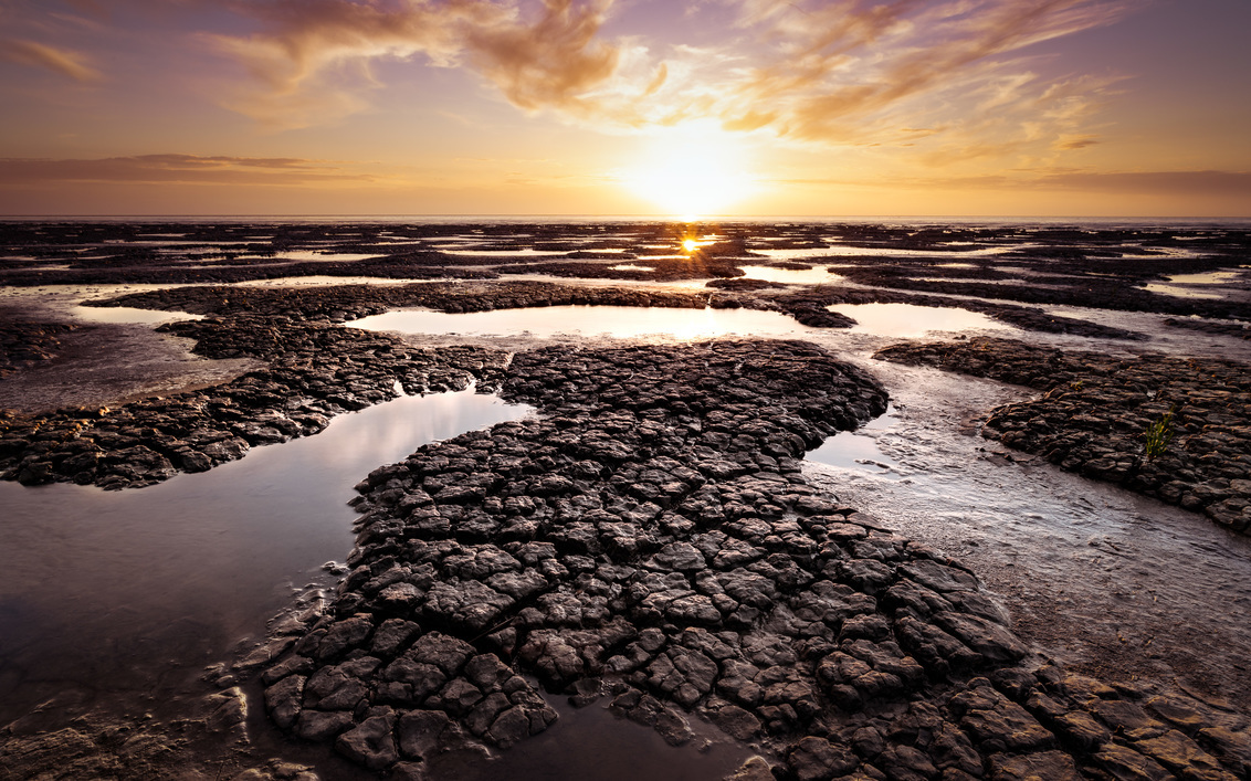 Sunspark on the tidepool - Fijne zonsondergang aan het Wad. - foto door renevierhuis op 01-07-2020 - deze foto bevat: lucht, wolken, zon, zee, water, natuur, geel, oranje, avond, zonsondergang, spiegeling, landschap, tegenlicht, kust, modder, waddenzee, friesland, droogte, scheuren, mudflats