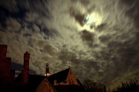 Maan beschijnt kerk door wolkendek