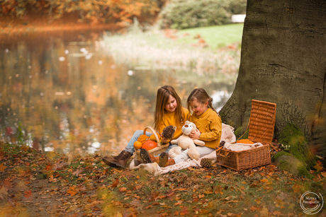 Spelende zusjes op kleedje in herfst bos