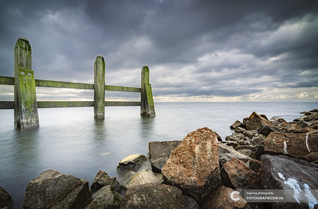 Havenhoofd met donkere wolken boven het IJsselmeer