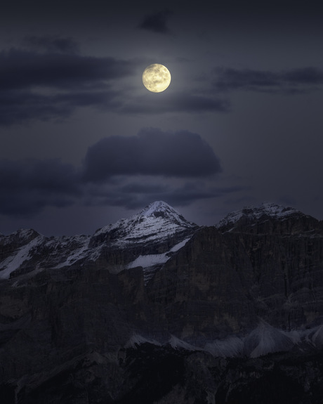 Volle maan boven een besneeuwde bergtop