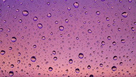 Morgenrood tesaam met regendruppels tegen het raam