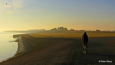 Mountainbiker in de gloed van zonsopgang langs het Wad bij Stroe.