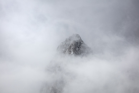 De majestueuze bergtop verborgen achter een sluier van wolken.