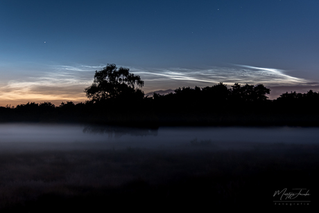 Lichtende nachtwolken boven een bedje van mist