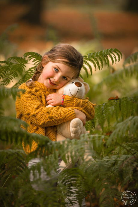 Meisje met knuffel tussen de varens