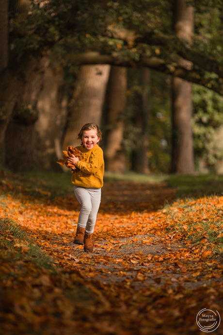 Rennend meisje met herfstbladeren in bos