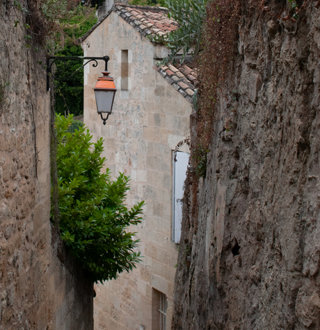 Oude roestige lantaarn hoog boven een steeg in Saint-Émilion
