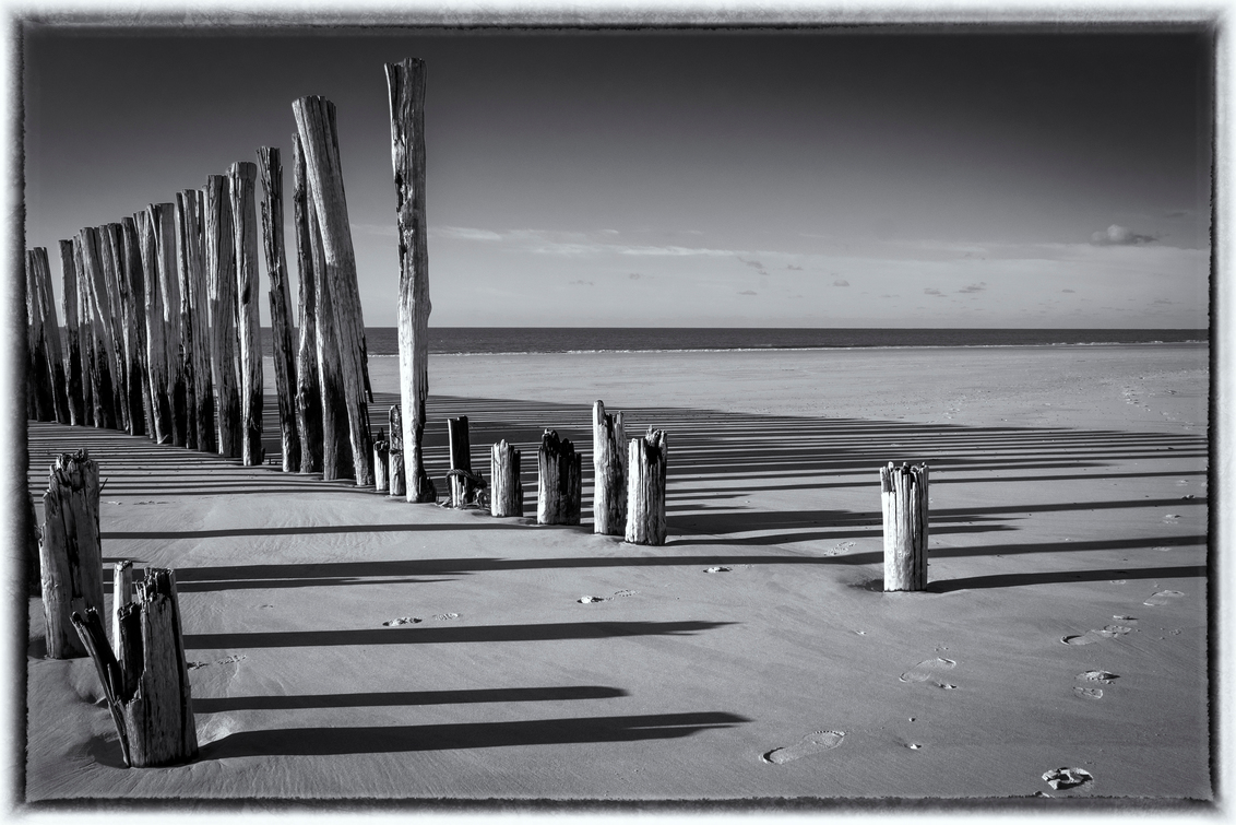 Lange schaduwen..... - Met Silver Efex Pro van Nik omgezet. - foto door apadmos op 29-11-2020 - deze foto bevat: strand, water, landschap, palen, zand, zeeland, kust, schaduwen, golfbreker, schouwen, Zwart/Wit, wesenschouwen