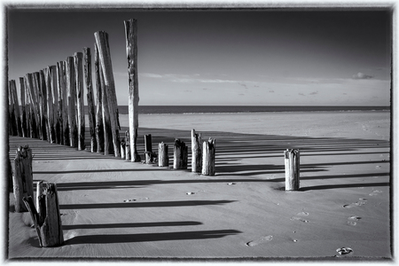 Lange schaduwen..... - Met Silver Efex Pro van Nik omgezet. - foto door apadmos op 29-11-2020 - deze foto bevat: strand, water, landschap, palen, zand, zeeland, kust, schaduwen, golfbreker, schouwen, Zwart/Wit, wesenschouwen