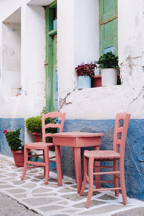 Griekse stoeltjes in pastelkleurig straatje op Samos