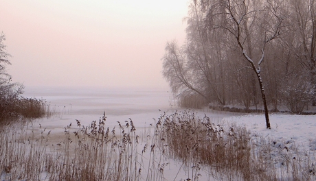 Zonsopkomst met mist boven een ijzig meer.