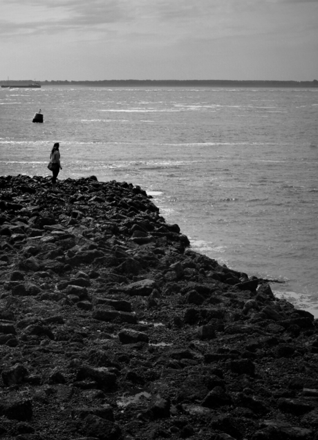 Jonge vrouw op rotsen uitkijkend over zee