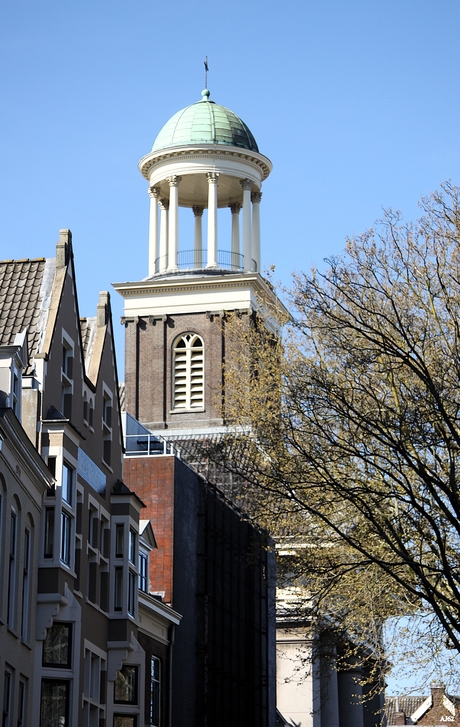 De toren rijkt hoog boven de grachtenpanden uit 
