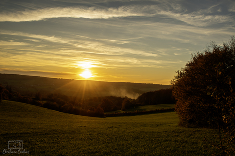 Het warme licht van de ondergaande zon rolt zachtjes over de glooiende Limburgse heuvels.