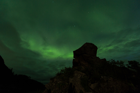 Noorderlicht achter een hoofdvormige rots op de Lofoten