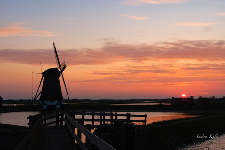 De lucht kleurt oranje,  bij molen het Noorden Texel. 
