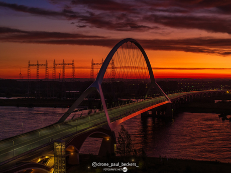 Net voor zonsopgang verlicht een rode gloed de brug.