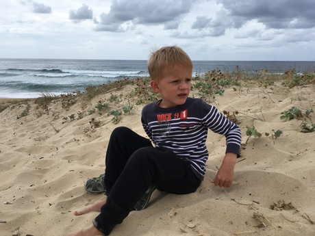 Kleuter op een duin met wolken en zee