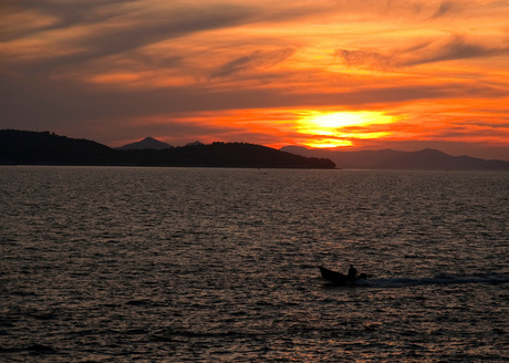 alone on the sea in a setting sun