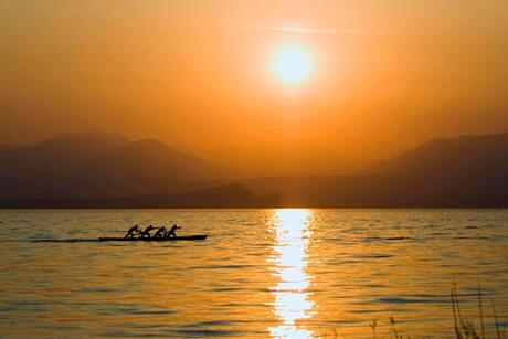 Roeiers op het Garda meer bij zonsondergang.