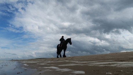 Strandrit langs dreigende wolken