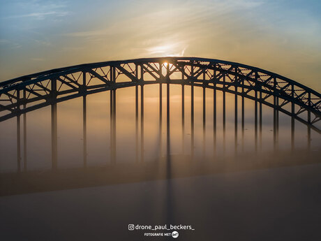 De zon komt door de mist heen bij de Waalbrug deze ochtend.