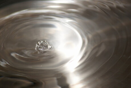 een drupel van een kraan valt in het water