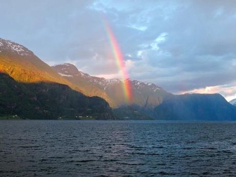 Regenboog door avondzon