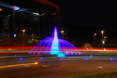 Verlichte fontein met passerende bus Hermes