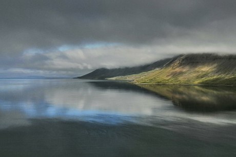 de zon breekt door in een mistige fjord