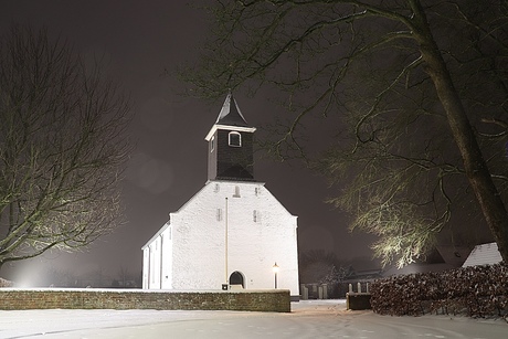 Kerkje in de sneeuw bij avond