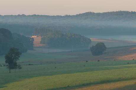 Zonsopgang over mistig Frans landschap.