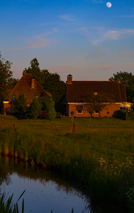 Boerderij bij zonsondergang en opkomende maan