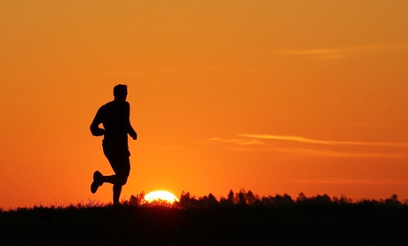 Hardloper op de dijk bij zonsondergang