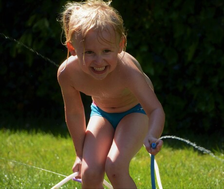 meisje-spelen-zomer-water-tuin