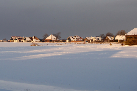 Zevenhuizen in zon met sneeuw en donkere lucht