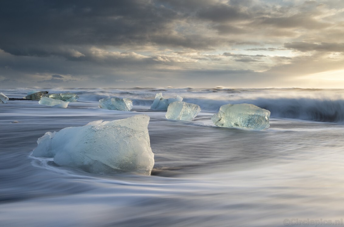 Go with the Flow - Vlak na zonsopkomst op Diamond Beach in IJsland. Door de storm waren er dit keer extreem veel brokken ijs, afkomstig van de nabije gletsjer, op het s - foto door weimaraan op 06-03-2020 - deze foto bevat: lucht, wolken, zon, strand, zee, water, natuur, licht, sneeuw, winter, ijs, landschap, zonsopkomst, zand, ijsland, golven, koud, kust, ijsbergen, lange sluitertijd, ijsblokken, diamond beach