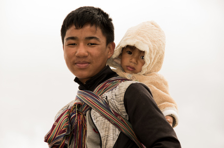 Vader met kind op zijn rug in Bhutan