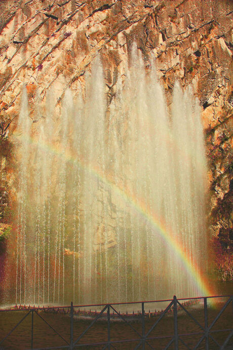 Fontein in avondzon met regenboog