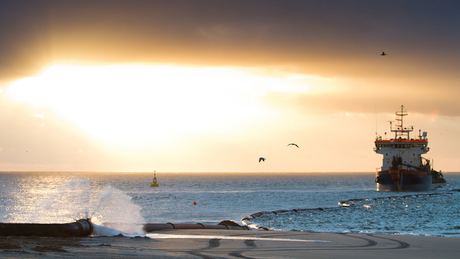 Zandopspuiting met zonsondergang