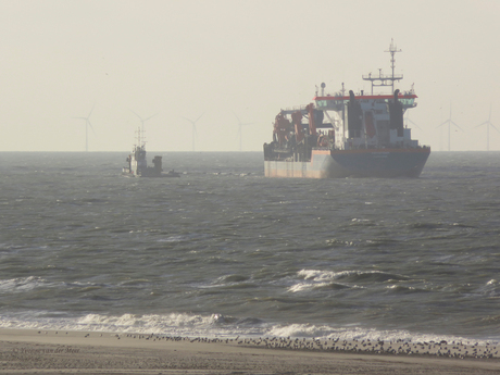 Zandschip loost via lange leiding naar het strand.