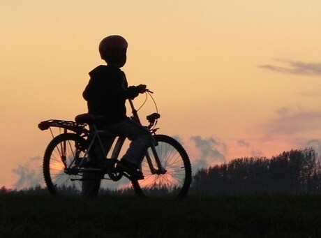 jochie kijkt naar zonsondergang over de polder