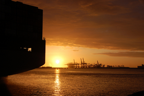 Containerschip en terminal bij zonsondergang