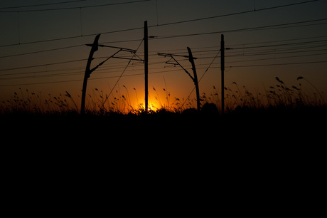 Spoorlijn langs de A15 bij zonsondergang